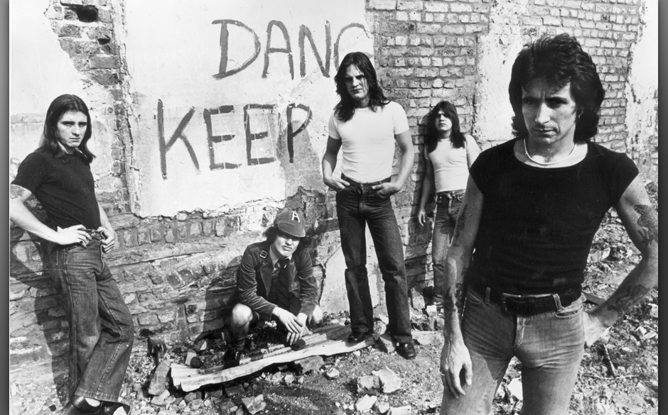 1977:  Promotional portrait of Australian hard-rock group AC/DC standing in front of a graffiti-covered brick wall, (L-R:) dr