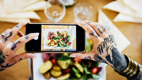 Tattooed woman taking pictures of their Food