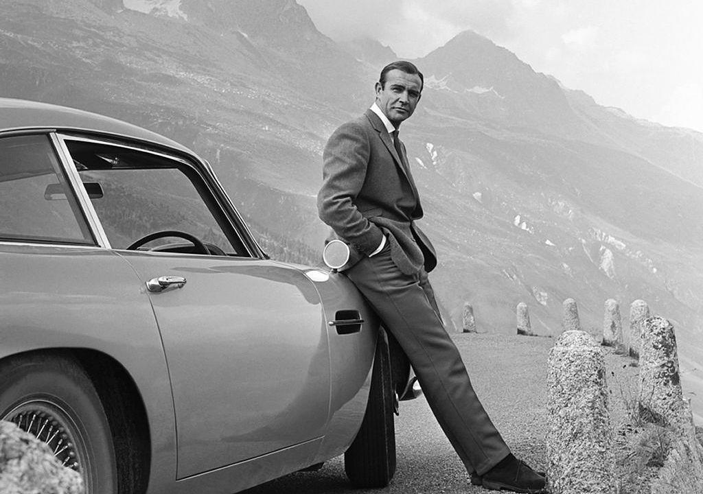 1964: Schauspieler Sean Connery posiert als James Bond neben seinem Aston Martin DB5 in einer Szene 'Goldfinger'.