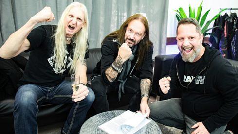 Oscar Dronjak (l.) und Joacim Cans von Hammerfall mit Marcus Hammer von Nuclear Blast bei der Vertragsunterzeichnung