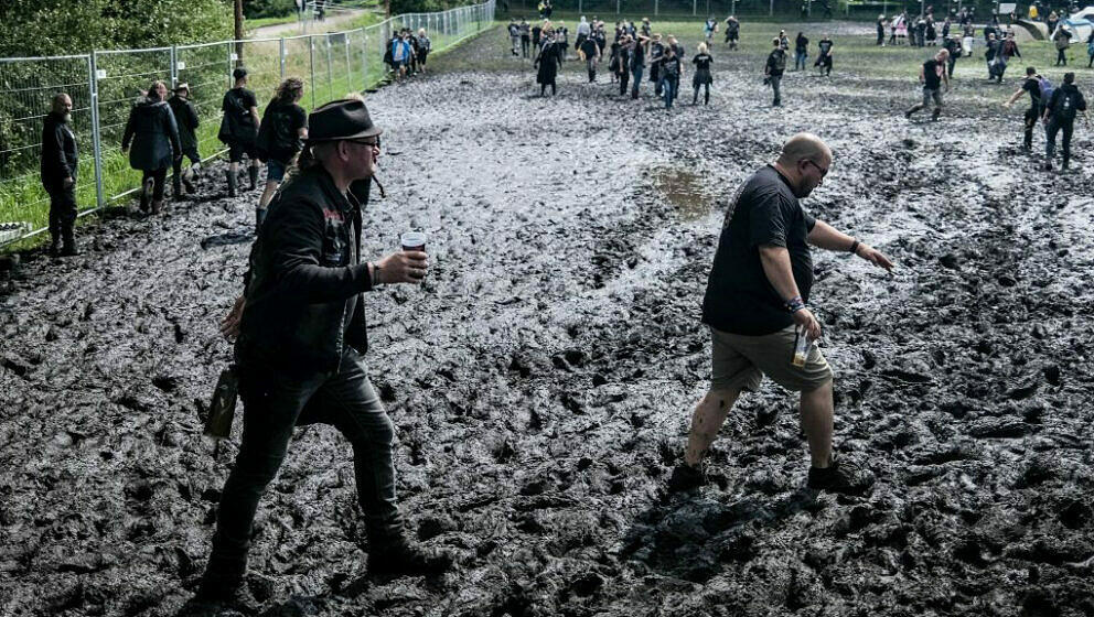 Festival-goers walk through mud as they arrive for the Wacken Open Air music festival in Wacken, northern Germany on August 1