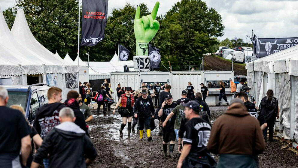Festival-goers make their way through mud as they arrive for the Wacken Open Air music festival in Wacken, northern Germany o