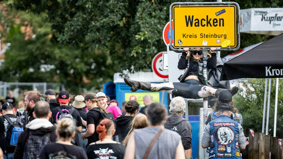 A festival-goer holds on to a town sign of Wacken ahead of the Wacken Open Air music festival in Wacken, northern Germany on 