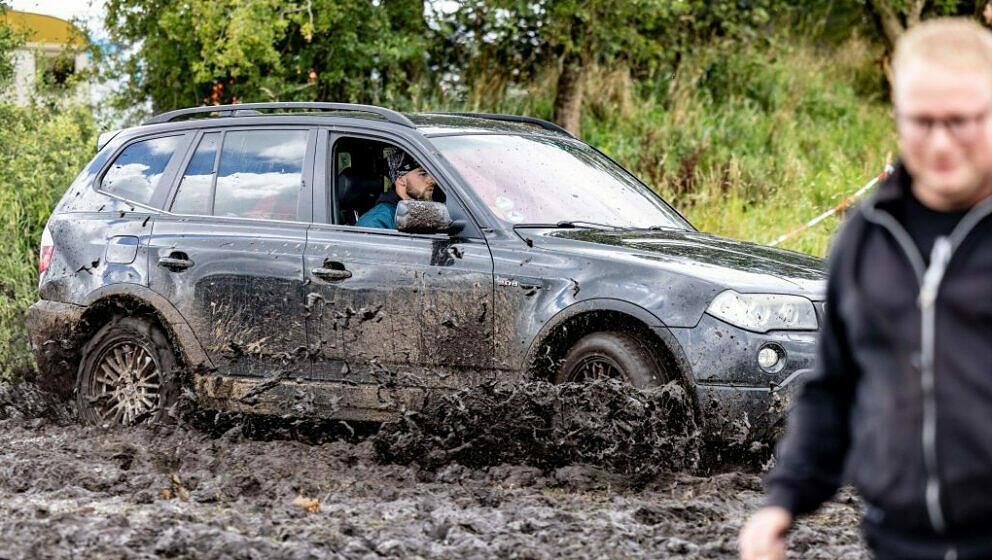 A festival-goer tries to park his car on the muddy festival grounds on the eve of the opening of the Wacken Open Air music fe