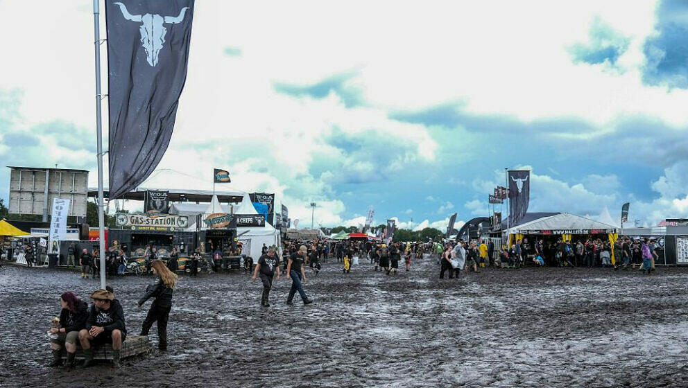 Festival-goers make their way through mud at the festival grounds ahead of the opening of the Wacken Open Air music festival 